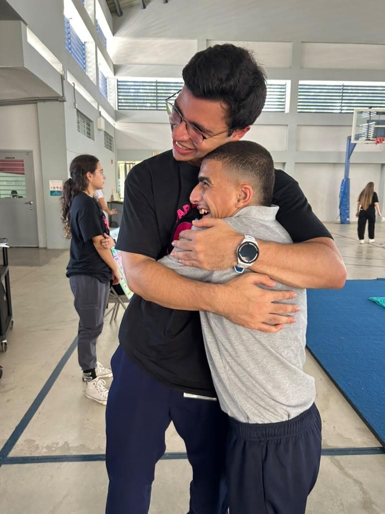 Dos personas sonríen mientras se abrazan en un gimnasio