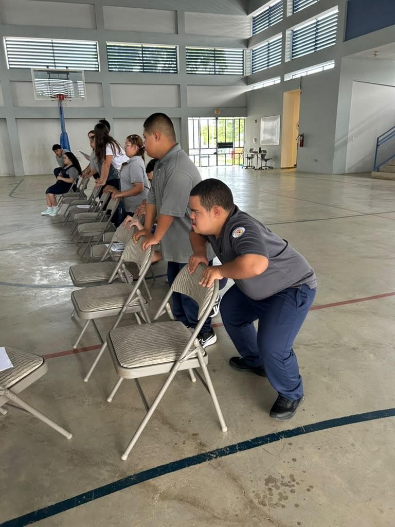 Participantes hacen ejercicio juntos con sillas en un gimnasio